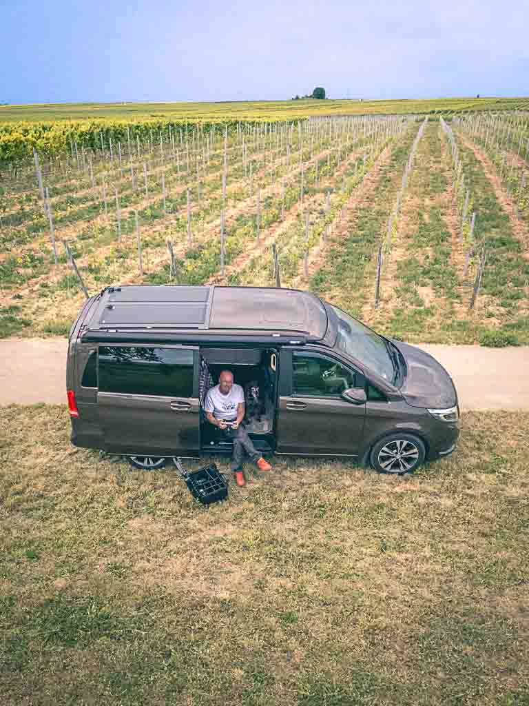 Weinberge Campingbus mit geöffneter Tür es sitzt jemand darin und fliegt Drohne