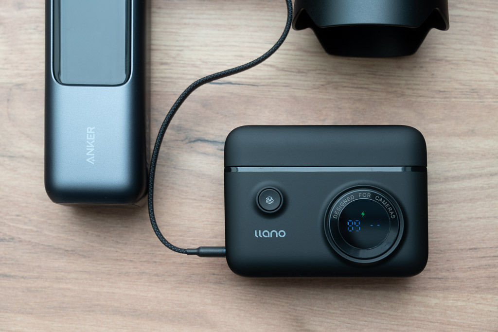 Llano 18W Smart-Digitalanzeige Ladegerät liegt auf einem Tisch daneben eine Anjer Powerbank, ein Kabel ist angeschlossen.